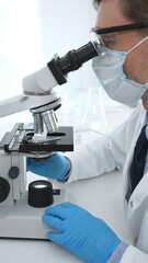 Man scientist wearing protective googles and blue gloves, is using microscope analyzing samples in modern laboratory doing scientific research. Medicine and science concept