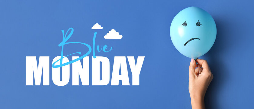 Hand holding balloon with drawn sad face on blue background