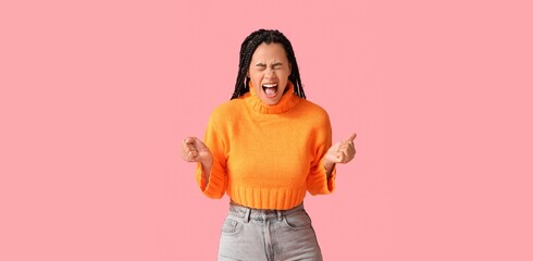 Angry African-American woman screaming on pink background