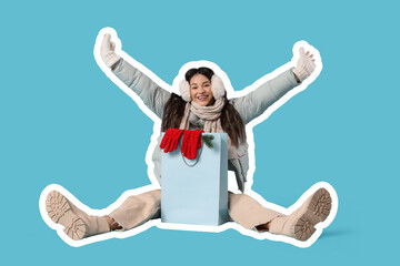 Beautiful young woman in warm clothes with shopping bag sitting on blue background