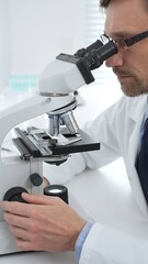 Medical scientist wearing glasses using microscope analyzing samples in modern laboratory doing scientific research. Medicine, health care and science concept