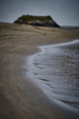Sand at dawn. Soft but warm colors, lipid water. Calm sea.