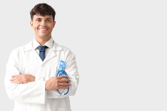 Male doctor with blue ribbon and stethoscope on light background. Prostate cancer awareness concept
