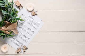 Composition with music sheets, burning candles and Christmas decorations on white wooden background