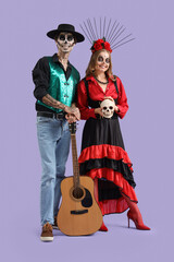 Young happy couple dressed for Mexico's Day of the Dead (El Dia de Muertos) with guitar and painted skull on purple background