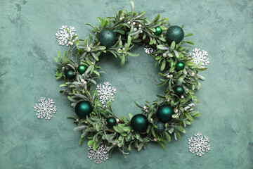 Obraz premium Christmas mistletoe wreath with beautiful decorations and snowflakes on grunge green background
