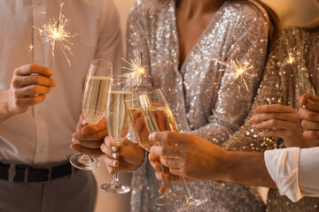 Young people with champagne and Christmas sparklers at party, closeup
