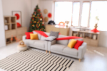 Blurred view of living room decorated for Japanese New Year celebration with sofas and fir tree