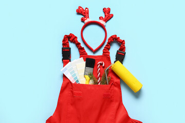 Painter's uniform with supplies and Christmas decor on blue background