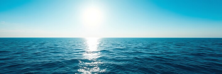 Obraz premium The bright sunlight glistens and sparkles on the calm, endless turquoise ocean water stretching to the horizon against a clear light blue sky.