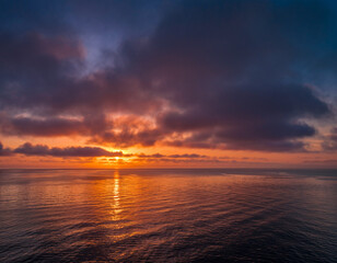 Naklejka premium Dramatic colorful sunset over the calm ocean water.