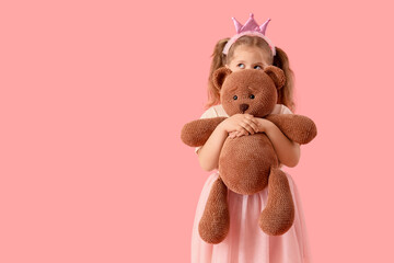 Cute little thoughtful girl in princess crown with teddy bear on pink background. International Hug Day
