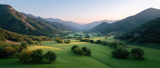 Lush Green Valley Illuminated by Golden Sunlight During a Serene Sunrise Over Rolling Hills and Distant Mountains