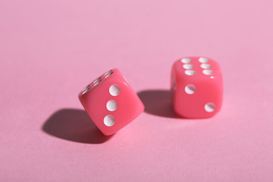 Game dices on pink background, closeup