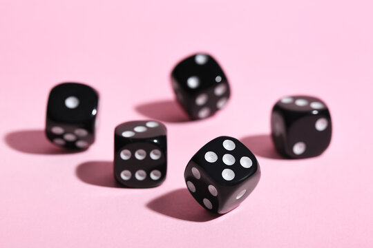 Black game dices on pink background