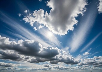 A high-resolution photograph of a bright blue sky filled with soft, fluffy cumulus clouds. The clouds appear voluminous and scattered across the horizon, illuminated by natural sunlight. Captured from