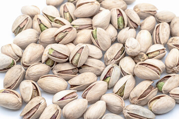 A pile of whole Italian pistachios in open shells showing their green nuts inside, highlighting...
