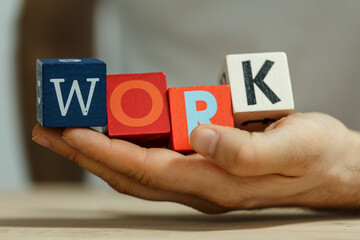 A hand holding wooden blocks that spells WORK. Conceptual image representing work and career. Good...