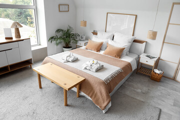 Interior of stylish hotel room with folded bathrobes on cozy bed