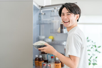 Young Asian man taking out ingredients from the refrigerator
