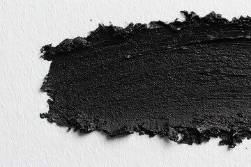 Glossy Black Glitter Paint Swatch on Textured White Background Creates an Abstract Design with a Rough Edge and Fine Grain Surface Texture