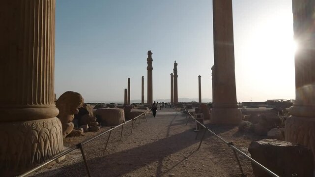 Wide tracking view of Persepolis, Iran: ancient stone gateways and columns under warm evening light. Achaemenid ruins and UNESCO heritage&mdash;archaeology and history across the desert plateau.