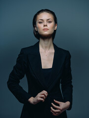 serious woman in black blazer posing confidently with dark background and moody lighting