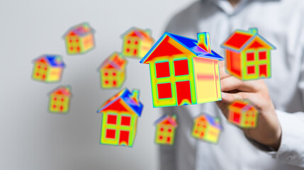 Conceptual image of a hand holding digital house models with a thermal imaging effect, suggesting...