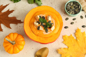 Delicious cream soup served in pumpkin on white grunge background