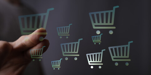 Person interacting with digital shopping cart icons representing online retail, e-commerce, and buying process in a digital world. © vegefox.com