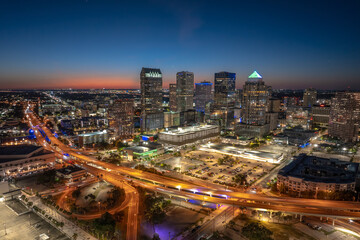 Obraz premium Tampa city in Florida with brightly illuminated highway traffic and skyscraper buildings in downtown district. American megapolis with business financial district at night.