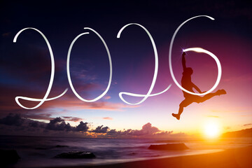 Silhouette of happy family jumping on the beach while celebrating new year of 2026 at dusk time