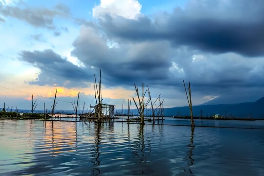 Serene Rawa Pening Lake With Wooden Poles and Small Fishing Hut Called Branjang At Sunset Under Dramatic Clouds