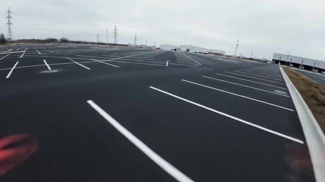 Empty parking lot with freshly painted white lines on dark asphalt, wide angle view.