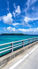 Obraz premium A serene view from a bridge over turquoise water to a distant island under blue sky