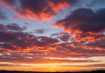 A peaceful evening sky with scattered cumulus clouds glowing in warm orange, pink, and light blue hues. The sun sets below the horizon, casting soft light rays upward. Captured in full HD from a groun