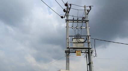 A yellow sign warns about high-voltage electricity and the dangers of hanging near high-voltage transformers.