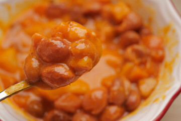 Warm bowl of baked beans served with spoon on a cozy table
