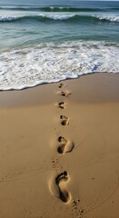 Footprints in the sand leading to the sea on a serene beach day