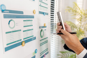 A business analyst examining charts and statistics on a whiteboard, using data-driven insights to guide financial strategy, business performance, and future organizational planning.