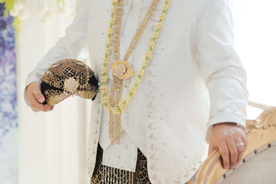 Javanese Groom in Traditional White Attire with Blangkon and Elaborate Jasmine Necklace