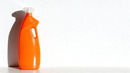 Orange cleaning bottle on white wall