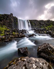 Scenic landscape featuring waterfall cascading over rocky cliffs