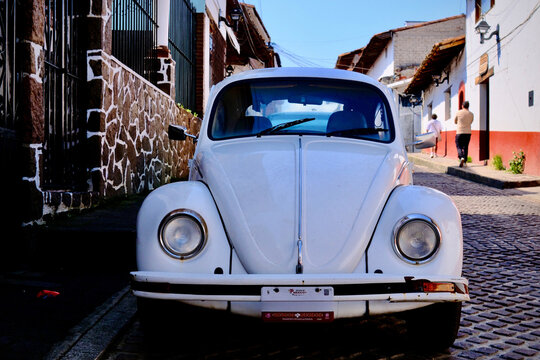Classic White Volkswagen Beetle on Cobblestone Street (Valle de Bravo, Mexico &ndash; October 25, 2025)
