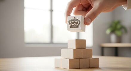 Hand stacking wooden blocks with crown symbol on a desk in bright office, representing leadership and business strategy, creating a sense of stability and success.