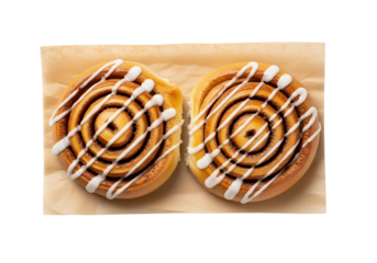 A top-down shot of two freshly baked, golden-brown cinnamon rolls, each with distinct spirals of cinnamon filling and drizzled with white icing, white background isolated