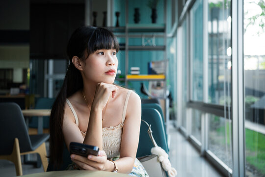 A woman is looking at her cell phone with a concerned expression on her face