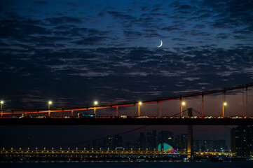 City Bridge at Night with Crescent Moon and Urban Lights