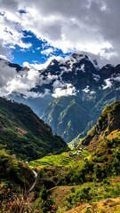 Obraz premium A steep valley with green terraces leads to mist-shrouded, rugged mountains