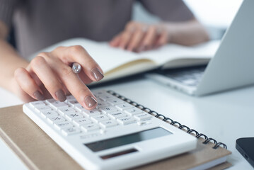 Close up woman hand using calculator to calculate home finance and writing note, accounting on...